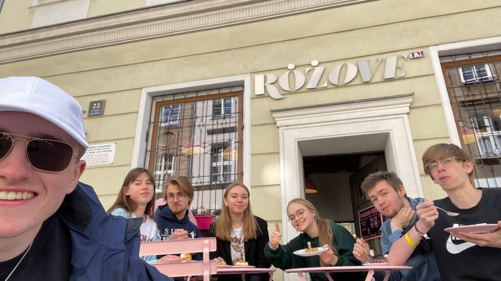 Zdjęcie grupowe przed kawiarnią, na którym wszyscy uczniowie się śmieją. 